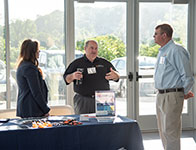Three people at a booth talking. Links to Gifts of Appreciated Securities